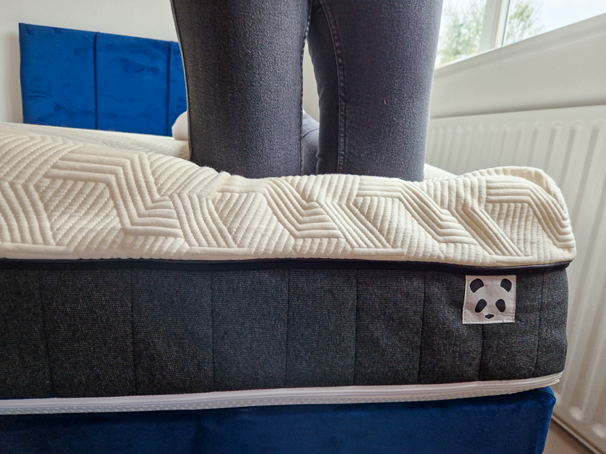 person kneeling at edge of mattress